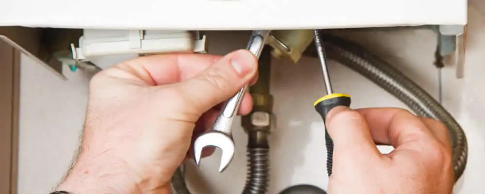 Boiler repair technician tightening pipe fittings and connections in Fresno, CA