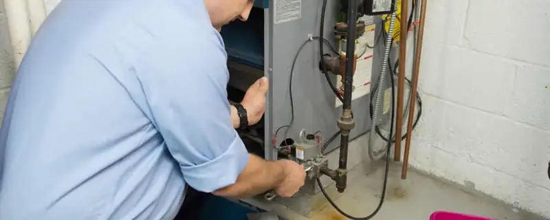 Furnace repair technician inspecting and servicing a home heating system in Fresno, CA