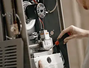 Furnace repair technician inspecting internal components and wiring in Fresno, CA