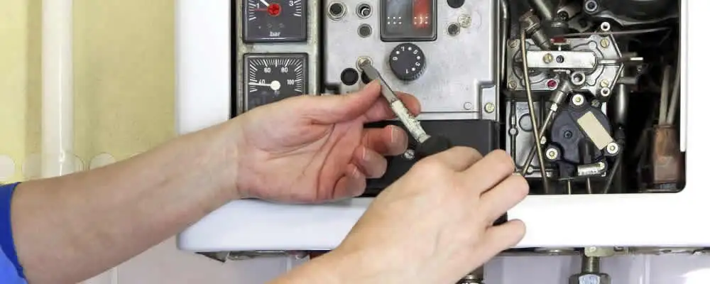 Heating repair technician adjusting boiler controls and components in Fresno, CA