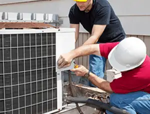 HVAC technicians repairing an outdoor AC unit on a rooftop in Fresno, CA