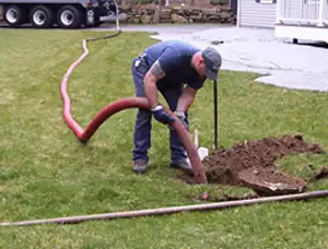 Septic pumping technician servicing a residential septic tank with a vacuum hose in Fresno, CA