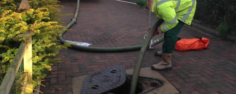 Septic tank cleaning technician servicing a septic tank with a vacuum hose in Fresno, CA