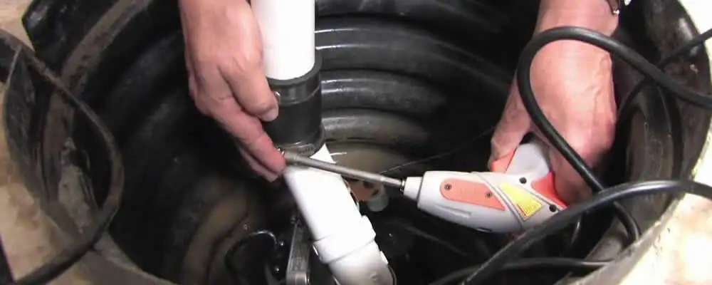 Sump pump installation technician connecting PVC discharge piping in Fresno, CA