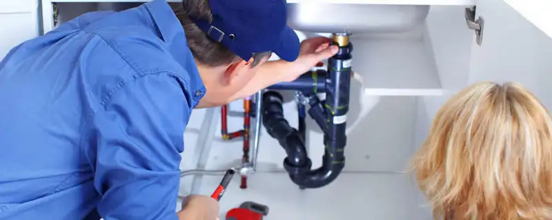 Plumber repairing under-sink drain pipes and fittings in Fresno, CA